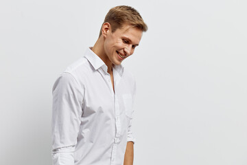 smiling young caucasian man in white shirt look down with happy cheerful expression isolated on...