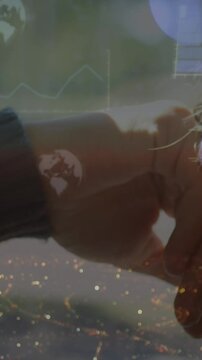 Animation of infographic interface and globe over caucasian listening music over headphones at home