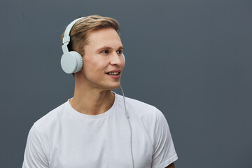 Smiling young caucasian man wear headphones listen music casual white t-shirt isolated gray...
