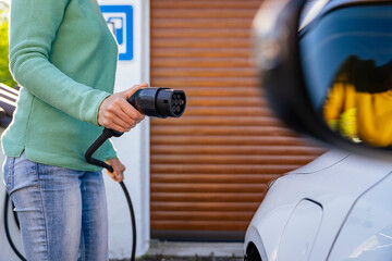 Person charging an electric car at home with a focus on sustainability and future energy solutions