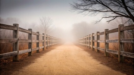 Obraz premium Wooden fence lines a dirt path disappearing into thick atmospheric fog and mist.