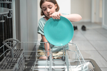 Child loads dishwasher. Everyday life concept,