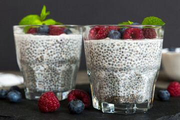 Healthy breakfast or morning with chia seeds vanilla pudding raspberry and blueberry berries on table background, vegetarian food, diet and health concept. Chia pudding with raspberry and blueberry
