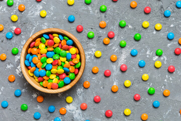 Multicolored candies in a bowl on a colored background. birthday and holiday concept. Top view with...