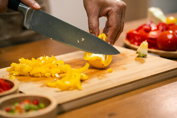 Asian man's hands cutting bell peppers in the kitchen