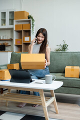Woman start up online seller owner at workplace. small business entrepreneur SME or freelance asian woman working with box at home.