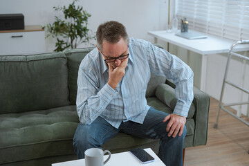 Senior man sitting in sofa, having depression, stress, irritability, and life problems.