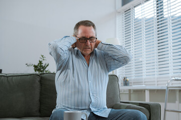 Senior man sitting in sofa, having depression, stress, irritability, and life problems.