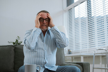 Senior man sitting in sofa, having depression, stress, irritability, and life problems.