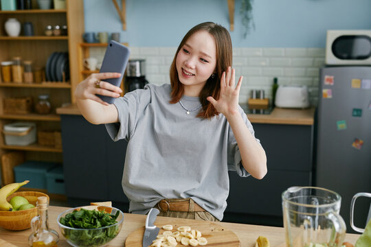 Young woman taking a selfie while preparing food in a modern kitchen
