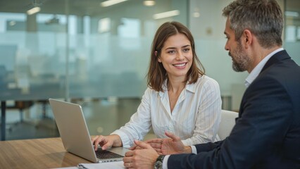 Woman and man collaborating on laptop in office business meeting