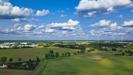 Vast agricultural landscape with wind turbines under a blue sky.