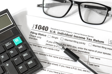 Close-up of a U.S. Individual Income Tax Return Form 1040 with a calculator, pen, and reading...