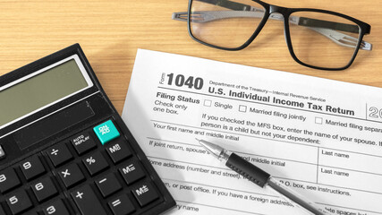 Close-up of a U.S. Individual Income Tax Return Form 1040 with a calculator, pen, and reading...