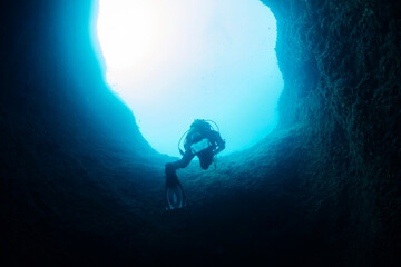 diver coming out of an underwater cave, concept of scuba diving and underwater adventure, copy...