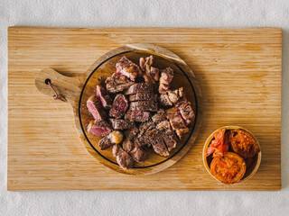 Beef steak medium rare with tomato on wooden plate.