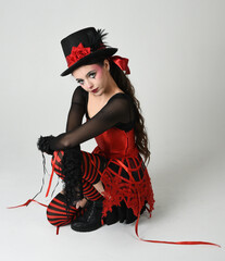 Burlesque circus performer, fantasy female model in halloween jester clown costume with top hat,...