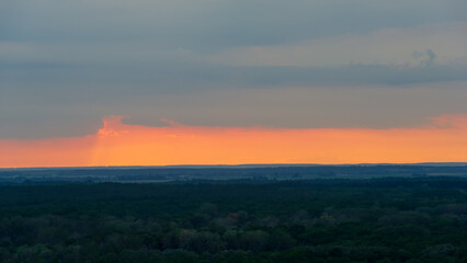 Milky sky and orange stripe in the sky on the horizon line at sunset.