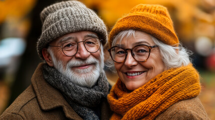 Happy elderly couple wearing warm knitted hats and scarves smiling outdoors during autumn season, cozy senior man and woman enjoying fall weather together