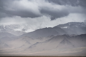 Panorama of mountain peaks and ridges with rocks and snow, with glaciers in the Tien Shan mountain system in the Pamirs in the highlands, cloudy weather