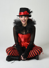Burlesque circus performer, fantasy female model in halloween jester clown costume with top hat,...