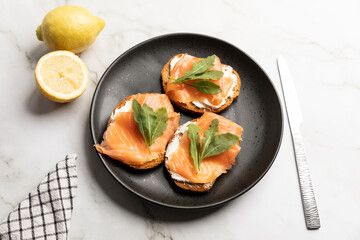 Smoked salmon toasts served with arugula on kitchen countertop background