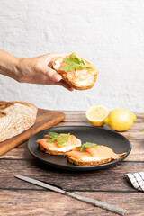 Hand holding smoked salmon toast served with arugula, healthy breakfast