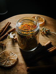 Colorful spices and aromatic ingredients displayed in a glass jar on a wooden surface