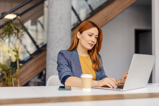 Portrait of focused businesswoman sitting at corporate office and working data analyzes on a laptop. - Powered by Adobe