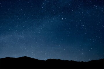 Obraz premium A stunning star-filled night sky above rolling hills, radiating serenity, wonder, and cosmic beauty