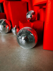 Decorative disco balls and vibrant red gifts arranged on a gray surface for festive celebration