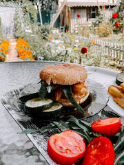 Delicious burger served with fresh vegetables in a vibrant garden setting