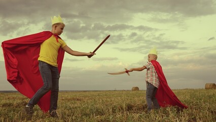children superheroes play with swords field kings knights. dream childhood. little kid and his...