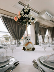 Table setting with decorative flowers and teddy bear for a celebration event indoors