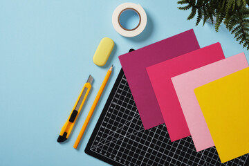 Workspace for paper crafts. Black cutting mat, colored paper, pencils, craft knife, ruler, tape....