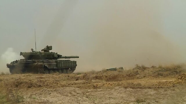 A tank stands in the field and shoots. The flame of a large-caliber projectile bursts out of the muzzle. Tactical tank exercises. Real war, fighting with the use of heavy armored vehicles. Tank battle