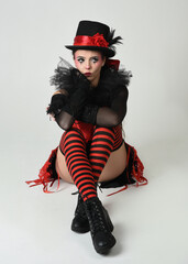 Burlesque circus performer, fantasy female model in halloween jester clown costume with top hat,...