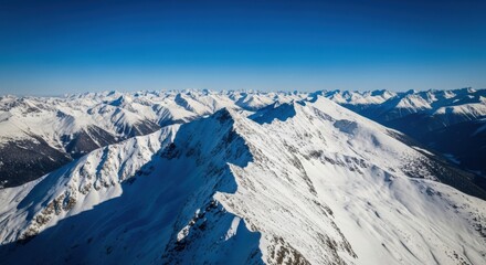 Obraz premium Majestic snow-covered mountain range under clear blue sky