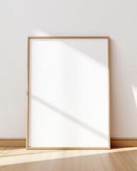 Blank poster mockup in wooden frame on white wall above a desk. Minimalist Scandinavian interior, natural light and soft shadows, clean layout.