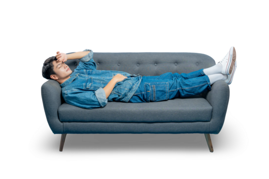 A tired or stressed young man lies on a sofa with his hand on his forehead, suffering from a headache or burnout.
