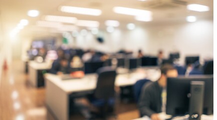 Photo of a blurry image captures a busy office environment, with numerous workers focused on their computer screens in a collaborative workspace