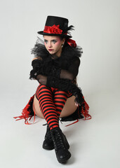 Burlesque circus performer, fantasy female model in halloween jester clown costume with top hat,...
