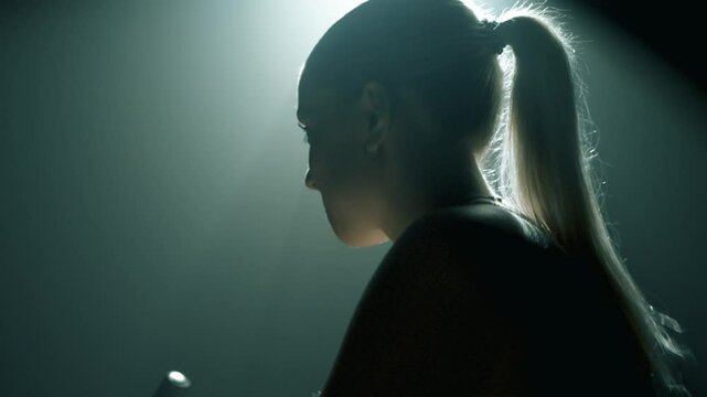 Kobieca twarz z profilu w czasie treningu na rowerze stacjonarnym na silowni z oswietleniem filmowym 