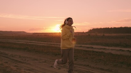 Beautiful girl runs against background pink sunset, doing morning fitness workout sunrise, woman...
