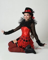 Burlesque circus performer, fantasy female model in halloween jester clown costume with top hat,...