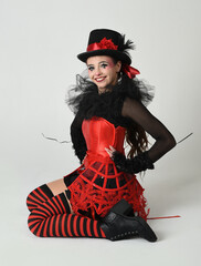 Burlesque circus performer, fantasy female model in halloween jester clown costume with top hat,...