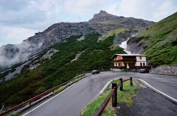 Mountain Landscape With Rustic House Along Winding Road And Waterfall