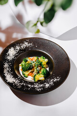 Colorful vegetable dish served in an elegant black bowl on a white table