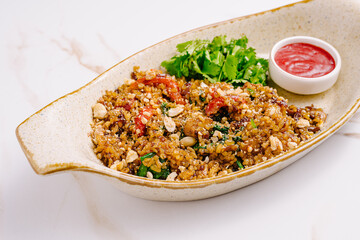 Flavorful quinoa salad garnished with herbs and sauce served in a bowl