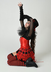 Burlesque circus performer, fantasy female model in halloween jester clown costume with top hat,...